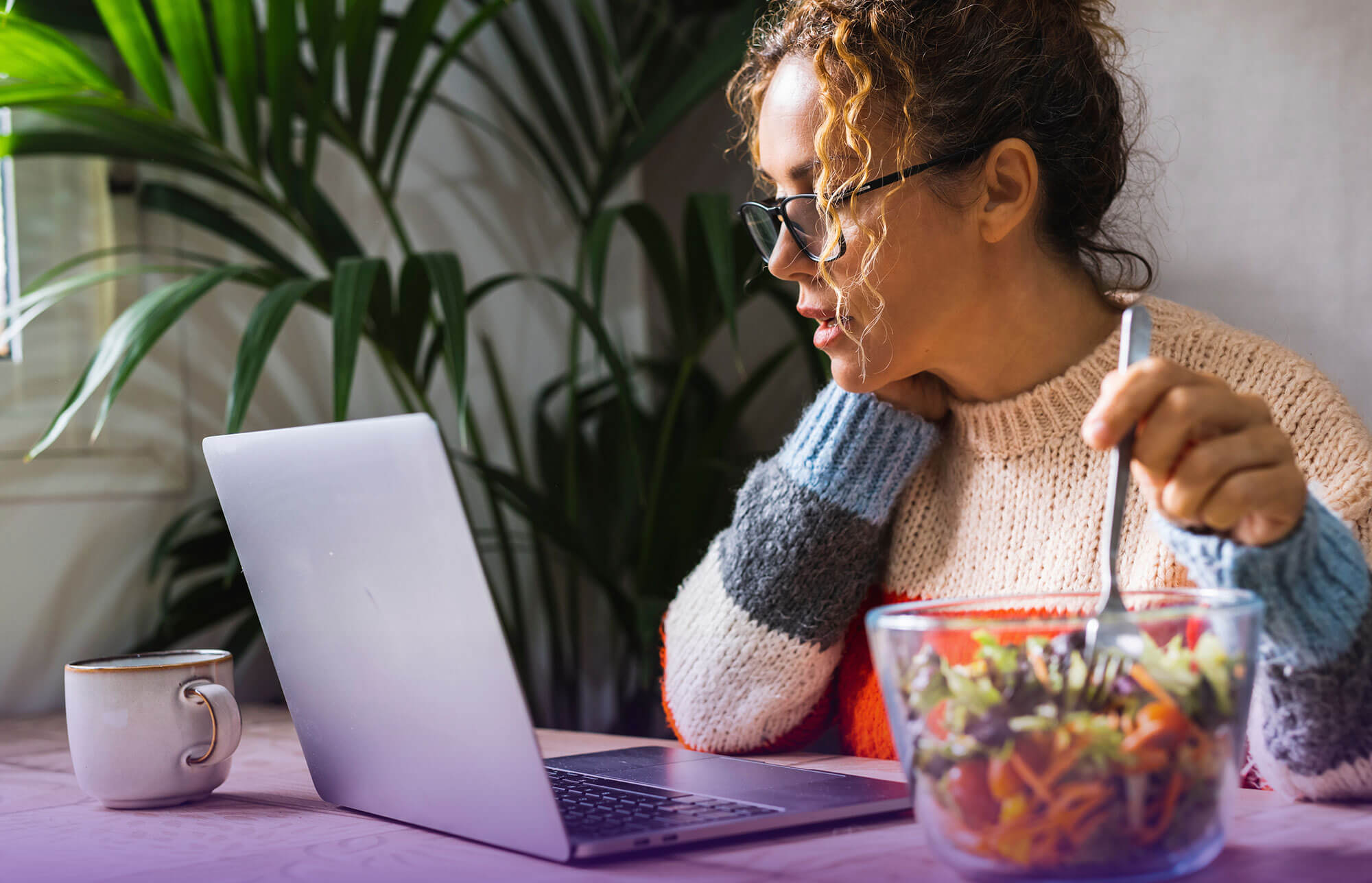 A glow getter working while enjoying a healthy salad - image